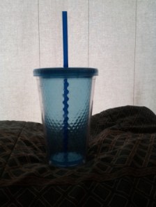 An empty reusable drink cup silhouetted in front of the window